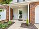 Charming townhome entrance featuring a brick facade, covered entryway, and tidy landscaping at 10063 Reindeer Way Ln, Charlotte, NC 28216