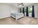 Cozy bedroom with a large bed, neutral carpet, ceiling fan, and ample natural light from the windows at 1632 Charles Raper Jonas Hwy, Mount Holly, NC 28120
