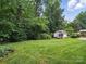 Expansive backyard with lush green grass and a charming shed surrounded by mature trees at 220 Lakeview Dr, Belmont, NC 28012