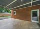 Covered patio with brick facade featuring concrete flooring and door to home at 220 Lakeview Dr, Belmont, NC 28012