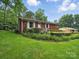 Red brick home featuring a tidy lawn and vibrant landscaping at 220 Lakeview Dr, Belmont, NC 28012