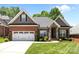 Charming brick home with a two-car garage, stone accents, manicured lawn and plentiful bushes and small shrubs at 4004 Saint Andrews Ct, Cramerton, NC 28032