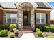 Close-up of the front door with stone archway, brick steps, and landscaped flower beds at 4004 Saint Andrews Ct, Cramerton, NC 28032