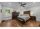Spacious main bedroom featuring dark wood furniture, tray ceiling with fan, and hardwood flooring at 4004 Saint Andrews Ct, Cramerton, NC 28032