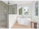 Elegant bathroom featuring a freestanding tub, glass-enclosed shower, and bright window with wood floors at 514 W Cama St, Charlotte, NC 28217