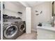 Functional laundry room featuring modern washer/dryer, folding space, storage shelves, and stylish sink at 600 Capella Ct, Gastonia, NC 28056