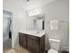 Clean bathroom with a single vanity, large mirror, toilet, and neutral color scheme at 6017 Fazio Ct, Harrisburg, NC 28075