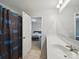 Bathroom with Carolina Panthers shower curtain, view of bedroom, single sink, and neutral paint at 6017 Fazio Ct, Harrisburg, NC 28075
