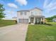 Charming two-story home featuring a well-manicured lawn, two-car garage, and inviting front porch at 6017 Fazio Ct, Harrisburg, NC 28075