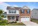 Inviting two-story home with a brick and siding exterior, offering a cozy front porch and a two-car garage at 7172 Teague Dr, Gastonia, NC 28056