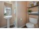 This half-bath features a pedestal sink, decorative shelving unit, toilet, and wood-look flooring at 7209 Cuddington Dr, Charlotte, NC 28215