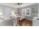 Cozy bedroom with hardwood floors, neutral walls, ceiling fan, and large window with white plantation shutters at 7600 Dunsmuir Ct, Cornelius, NC 28031