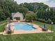 Aerial view of a refreshing community pool with ample seating, surrounded by lush landscaping and green lawns at 7600 Dunsmuir Ct, Cornelius, NC 28031