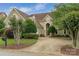 Charming home exterior with a circular driveway, lush landscaping, and mature trees at 7600 Dunsmuir Ct, Cornelius, NC 28031