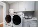 Well-lit laundry room with modern washer and dryer, sink, white cabinets, and marble countertop at 7600 Dunsmuir Ct, Cornelius, NC 28031