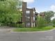 Exterior of a multi-level home with wood paneling, mature trees, and manicured bushes at 8202 Cedar Glen Dr, Charlotte, NC 28212