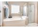 Bright bathroom showcasing a soaking tub with window and glass shower enclosure, offering relaxation and convenience at 9814 Tompkins Ln, Waxhaw, NC 28173