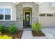 Front door featuring stone archway, lush landscaping, and direct access to the two-car garage at 9842 Quercus Ln, Huntersville, NC 28078