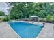 Refreshing backyard pool with lounge area and a white picket fence surrounded by lush greenery, perfect for relaxation at 10304 Squires Way # 18, Cornelius, NC 28031