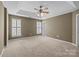Spacious bedroom with a tray ceiling, ceiling fan, and windows with white shutters at 10455 Alexander Martin Ave, Charlotte, NC 28277