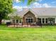 Back of home with a patio, complemented by a well-manicured lawn and stone accents at 10875 Casetta Dr, Matthews, NC 28105