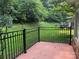 Backyard view from patio with a wrought iron fence overlooking manicured lawn with mature trees at 10875 Casetta Dr, Matthews, NC 28105