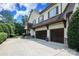 Three car garage with a concrete driveway, gray house with black shutters, and stone accents at 1103 Mapesbury Ln, Waxhaw, NC 28173