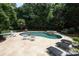 Backyard pool area with travertine patio, lounge chairs, outdoor furniture and wooded perimeter for privacy at 1103 Mapesbury Ln, Waxhaw, NC 28173