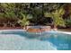 Beautiful in-ground pool with a stone waterfall feature and mature landscaping, creating a serene outdoor oasis at 1103 Mapesbury Ln, Waxhaw, NC 28173