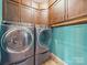 Convenient laundry room with modern front-load washer and dryer, wooden cabinets, and blue accent wall at 11225 Island View Ln, Lancaster, SC 29720