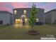 Fenced backyard with lawn, young tree, and patio at dusk at 12536 Stoneybrook Pkwy, Huntersville, NC 28078