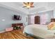 Well-lit bedroom with hardwood floors, ceiling fan, tv, and light pink accents at 126 Rocky Trail Ct, Fort Mill, SC 29715