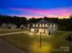 Beautiful two-story home featuring a well-manicured lawn, illuminated by outdoor lighting at dusk at 126 Still Creek Dr, Mooresville, NC 28115