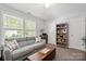 Cozy living room featuring a comfortable gray sofa and bright natural light from the double windows at 12663 Windyedge Rd, Huntersville, NC 28078