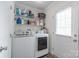Well-lit laundry room equipped with a white washer and dryer set, shelving storage, and a bright exterior door at 1316 Wiscassett St, Albemarle, NC 28001