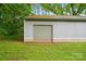 Exterior shot of a grey shed with a roll up door and nice green grass at 1621 California Rd, York, SC 29745