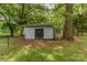 Exterior view of a storage shed with black doors, located in a fenced backyard surrounded by trees at 1867 Shannon Dr, Conover, NC 28613