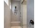 Glass-enclosed walk-in shower features stone floors, tiled walls, and a built-in seat at 215 Pintail Dr, Monroe, NC 28110