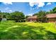 Lush backyard featuring green grass, trees, a brick house, and a patio set, perfect for entertaining at 2209 Cardinal Loop, Stanley, NC 28164