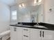 Bathroom with a large mirror, white cabinets, and double sinks with black countertop at 231 Brook Se Ave, Concord, NC 28025