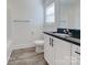 Bright bathroom with wood-look flooring, white cabinets, and black countertops at 231 Brook Se Ave, Concord, NC 28025
