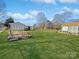A large green backyard has grass and several sheds on a sunny day with cloudy blue skies at 2316 Woodfield Cir, Gastonia, NC 28056