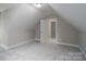 Finished attic space with neutral paint, carpet flooring, natural light, and access door at 248 Pioneer Dr, Mount Gilead, NC 27306