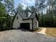 View of the home's exterior showcasing its architectural details, black garage door, stone, and gravel driveway at 248 Pioneer Dr, Mount Gilead, NC 27306