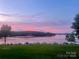 Scenic lake view with boats docked and a beautiful pink sunset sky in the background at 248 Pioneer Dr, Mount Gilead, NC 27306