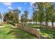 Spacious backyard with stone wall and trees, offering lake access at 25566 Seagull Dr, Lancaster, SC 29720