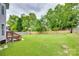 A spacious and level backyard is framed by lush trees and a wooden fence at 3725 Leela Palace Way, Fort Mill, SC 29708