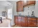 Dry bar with cherry cabinets, granite countertop, tiled backsplash, and stainless steel sink in an open floor plan at 3725 Leela Palace Way, Fort Mill, SC 29708