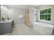 Bathroom showcasing a sleek vanity, glass-enclosed shower, and a freestanding soaking tub with a window at 415 Glandon Ct, Fort Mill, SC 29708