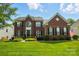 Beautiful two story red brick home with manicured lawn, landscaping, and black shutters under a cloudy blue sky at 415 Glandon Ct, Fort Mill, SC 29708